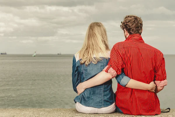 Coppia seduta abbracciata sulla riva del mare — Foto Stock