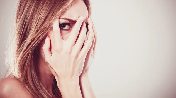 Medo assustado mulher espreitando através de seus dedos — Fotografia de Stock