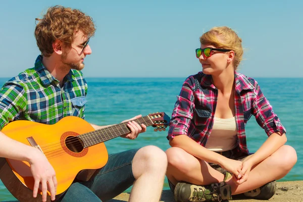 Joven tocando la guitarra a su novia junto al mar — Foto de Stock