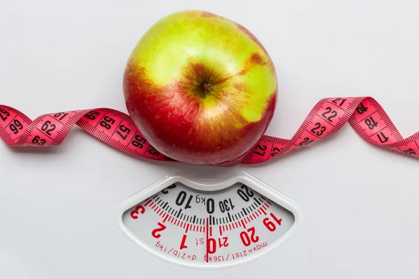 Apple with measuring tape on weight scale — Stock Photo, Image