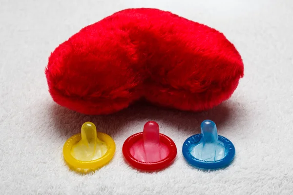 Kolorowy prezerwatywy i czerwone serce — Zdjęcie stockowe