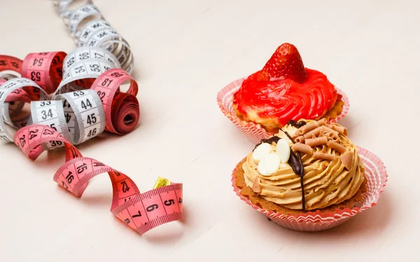 Cupcakes with measuring tape on table — Stock Photo, Image