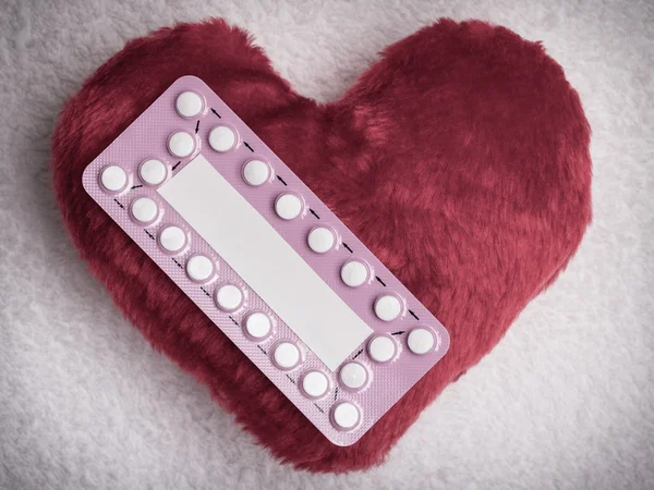 Усні протизаплідні таблетки на червоному серці — стокове фото