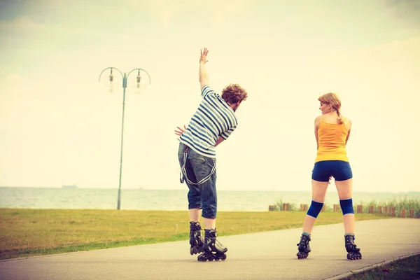 Pareja joven en patines de ruedas montando al aire libre — Foto de Stock