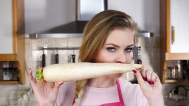 Beyaz turp kökü tutan ve onu koklayan genç ve güzel bir kadın. Sağlıklı gıda konsepti.