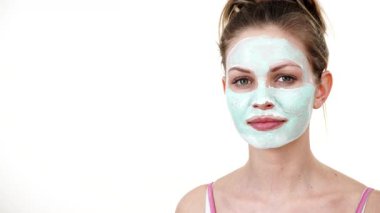 Yüzünde beyaz yeşil çamur maskesi olan genç bir kadın. Genç kız yağlı cildiyle ilgileniyor, gözenekleri temizliyor. Güzellik tedavisi. Cilt bakımı.