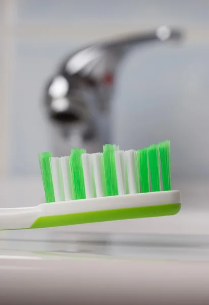 Escova de dentes verde no banheiro na pia — Fotografia de Stock