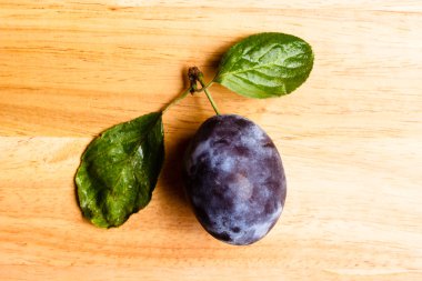 Ahşap masa üzerinde yeşil yaprakları ile tek Erik meyve