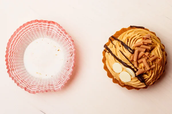 Pastelito de comida dulce y forma de papel en la mesa — Foto de Stock