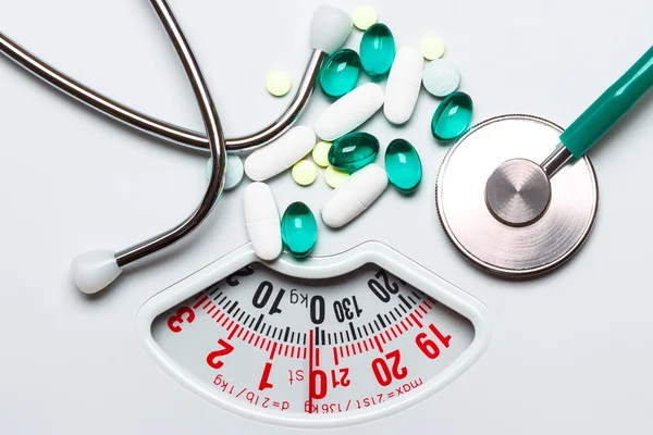 Comprimidos e estetoscópio em escalas. Serviços de saúde — Fotografia de Stock