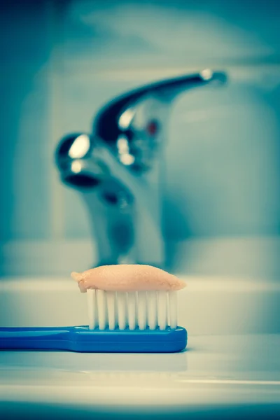 Escova de dentes azul com pasta no banheiro na pia — Fotografia de Stock