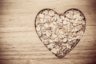 Yulaf gevreği kalp şeklinde ahşap yüzeyde.