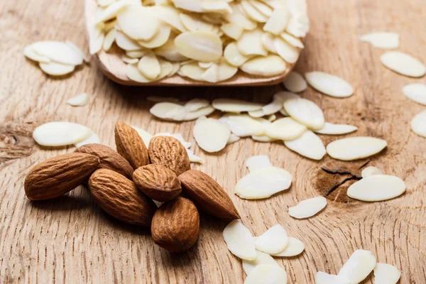 En rodajas y almendras crudas enteras sobre superficie de madera —  Fotos de Stock