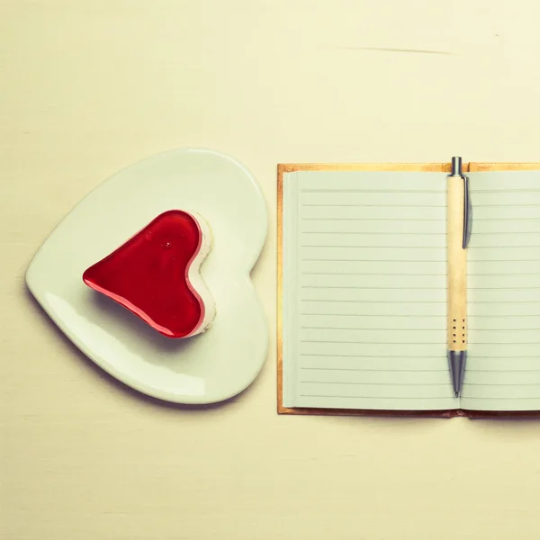 Jelly cake in heart form and notebook — Stock Photo, Image