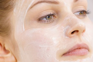 Yüzünde krem kozmetik, maske ve nem olan genç bir kadın. Güzellik tedavisi. Cilt bakımı.