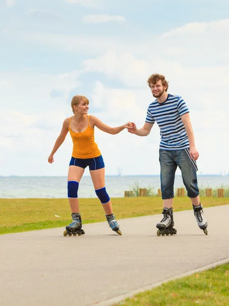 Jovem casal em patins andando ao ar livre — Fotografia de Stock