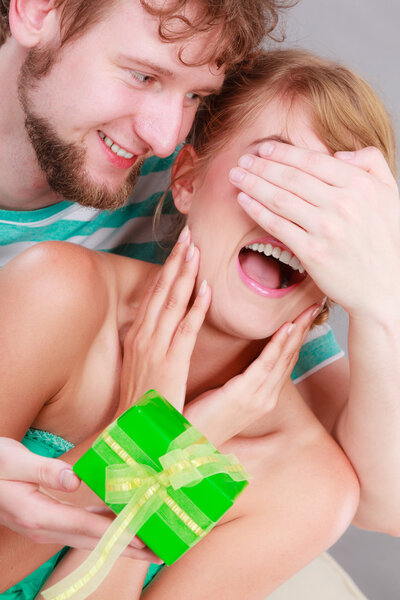 Молодой человек дарит женщине подарочную коробку
