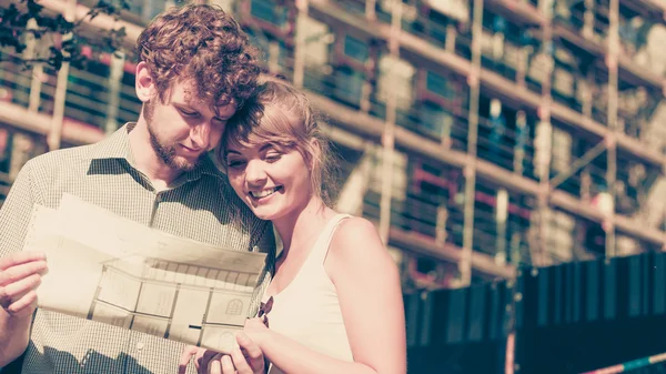 Casal na frente da casa nova com projeto de planta — Fotografia de Stock