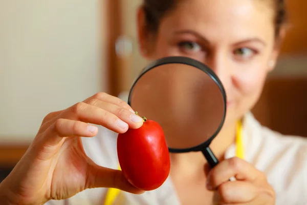 Mulher inspecionando tomate com lupa . — Fotografia de Stock