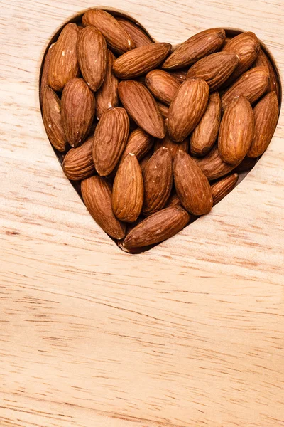 Mandorle a forma di cuore su fondo superficie in legno — Foto Stock