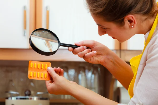 Mujer inspeccionando píldoras con lupa . —  Fotos de Stock