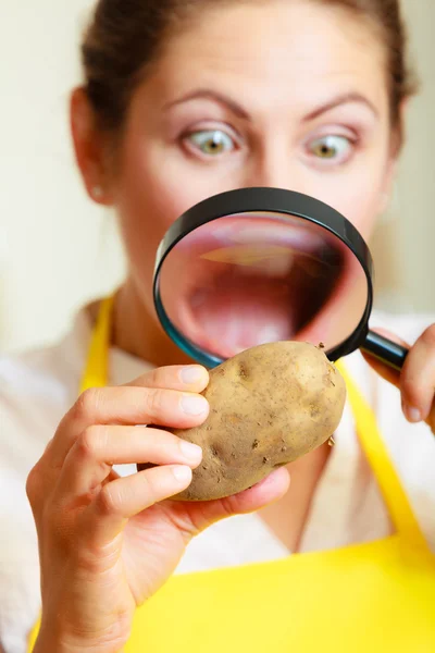 Женщина осматривает картофель с лупой . — стоковое фото