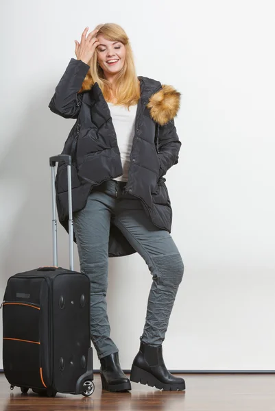 Gelukkig jonge vrouw in warme jas met koffer. — Stockfoto