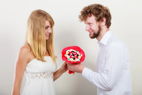 お菓子たくさん花を持つ幸せなカップル。愛. — ストック写真