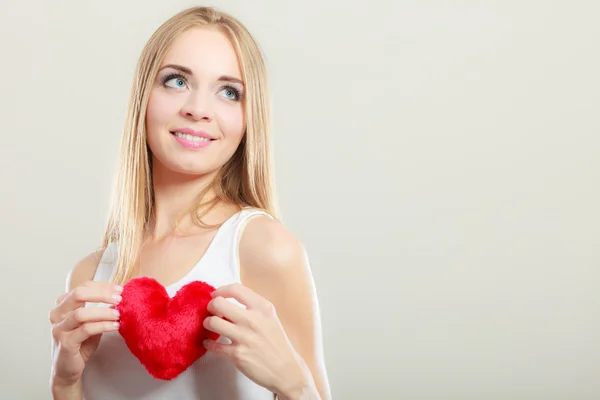 Mujer sonriente sosteniendo el símbolo de amor corazón rojo — Foto de Stock