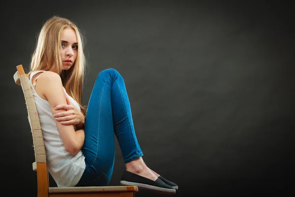 Jovem mulher triste sentada na cadeira — Fotografia de Stock