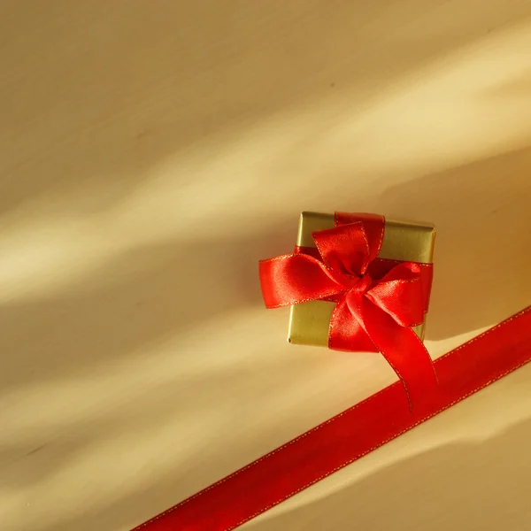 Petite boîte dorée avec cadeau nœud rouge — Photo