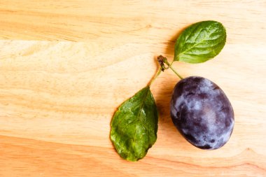 Ahşap masa üzerinde yeşil yaprakları ile tek Erik meyve