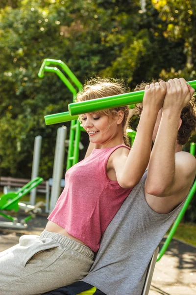 Man and woman exercising on pulldown outdoor. — Stock Photo, Image