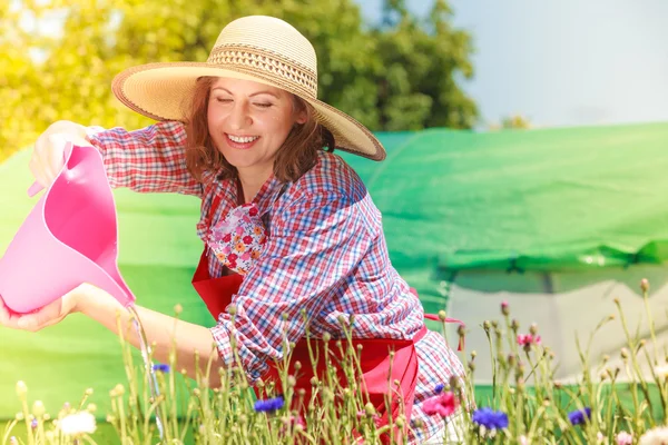 Mujer regando flores en el jardín — Foto de Stock