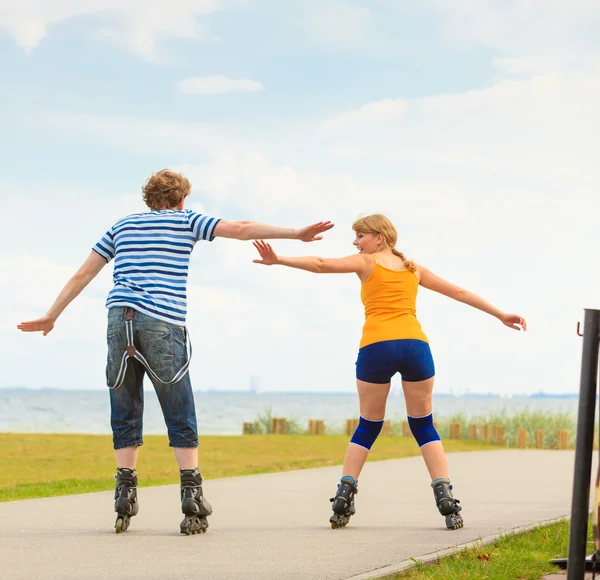 Pareja joven en patines de ruedas montando al aire libre — Foto de Stock