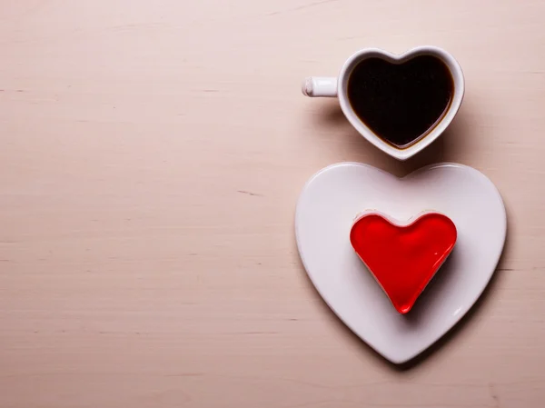 Чашка кофе в форме сердца и торт на деревянной поверхности — стоковое фото
