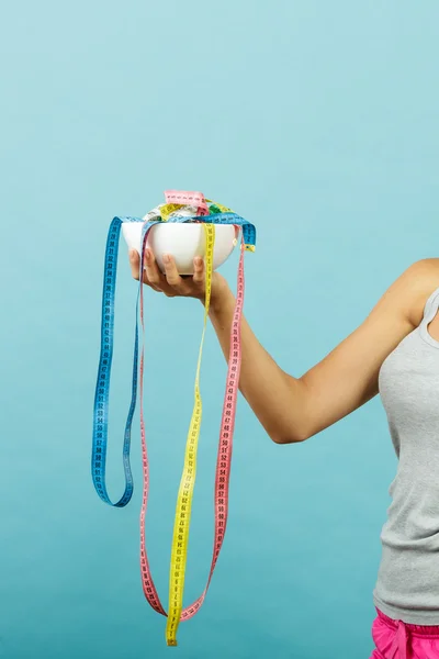 Fit girl holds bowl with many measuring tapes — Stock Photo, Image