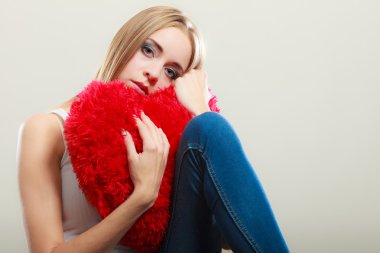 Kırmızı kalp yastık tutan mutsuz mutsuz kadın