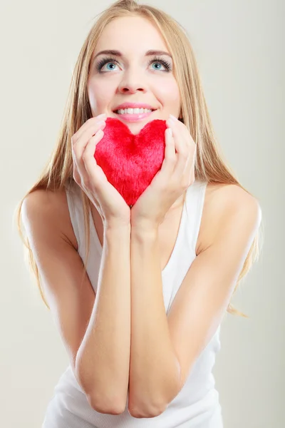 Mujer sonriente sosteniendo el símbolo de amor corazón rojo —  Fotos de Stock