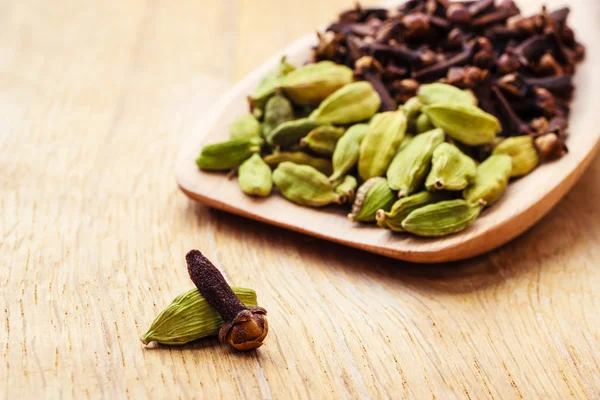 Kardemom peulen en kruidnagelen op houten lepel — Stockfoto