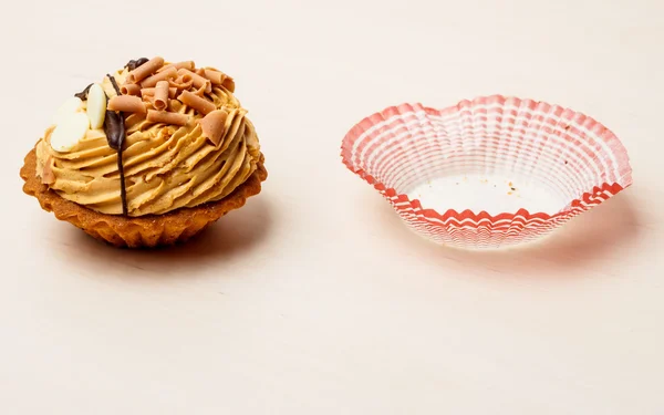 Pastelito de comida dulce y forma de papel en la mesa — Foto de Stock