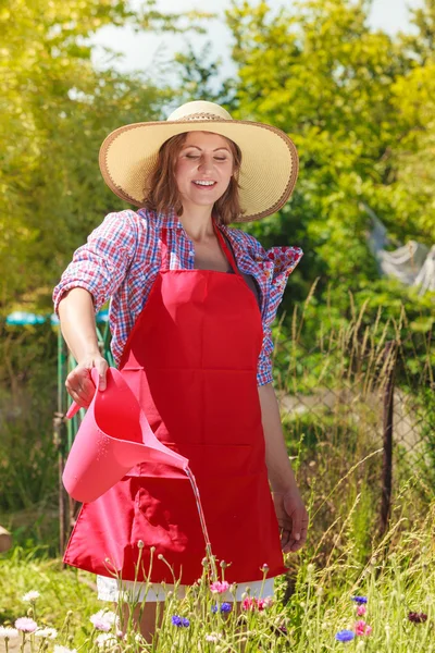 Mujer regando flores en el jardín — Foto de Stock