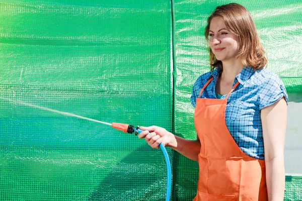 Woman watering the garden with hose — Stock Photo, Image