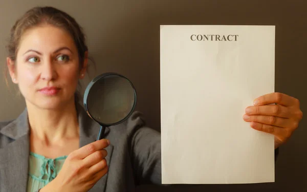Деловая женщина с контрактом и лупой — стоковое фото