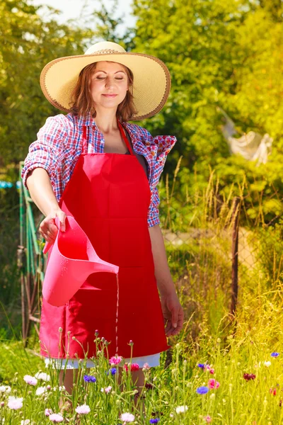 Mujer regando flores en el jardín — Foto de Stock