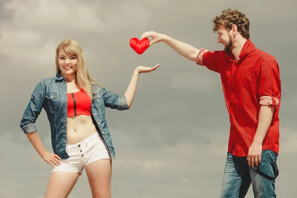 Pareja en amor sostiene rojo corazón al aire libre — Foto de Stock