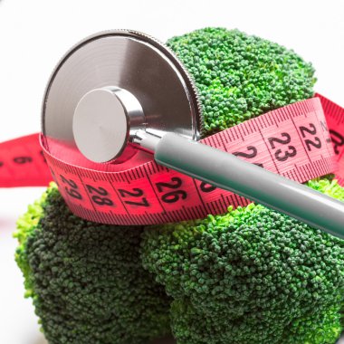 Broccoli with measuring tape and stethoscope . Dieting