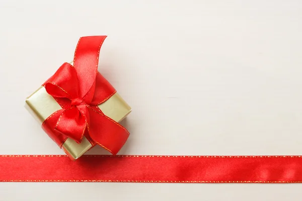 Kleine goldene Schachtel mit Geschenk gebunden rote Schleife — Stockfoto