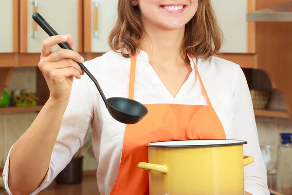 Mujer con cucharón y olla en la cocina — Foto de Stock