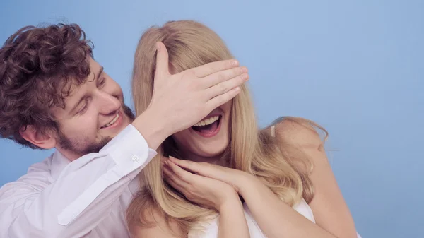 Playful man covering woman eyes.